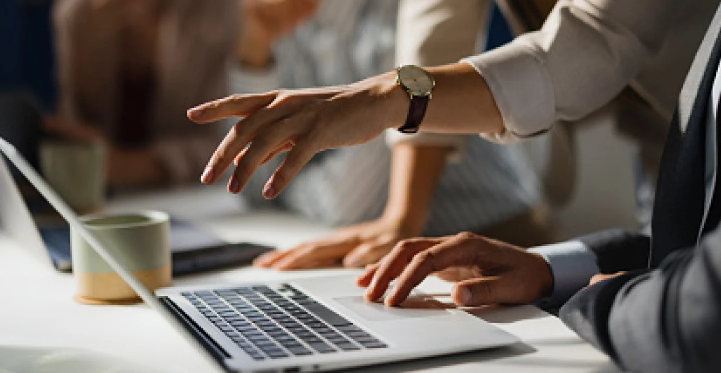Two credit professionals reviewing trade credit research together on a laptop